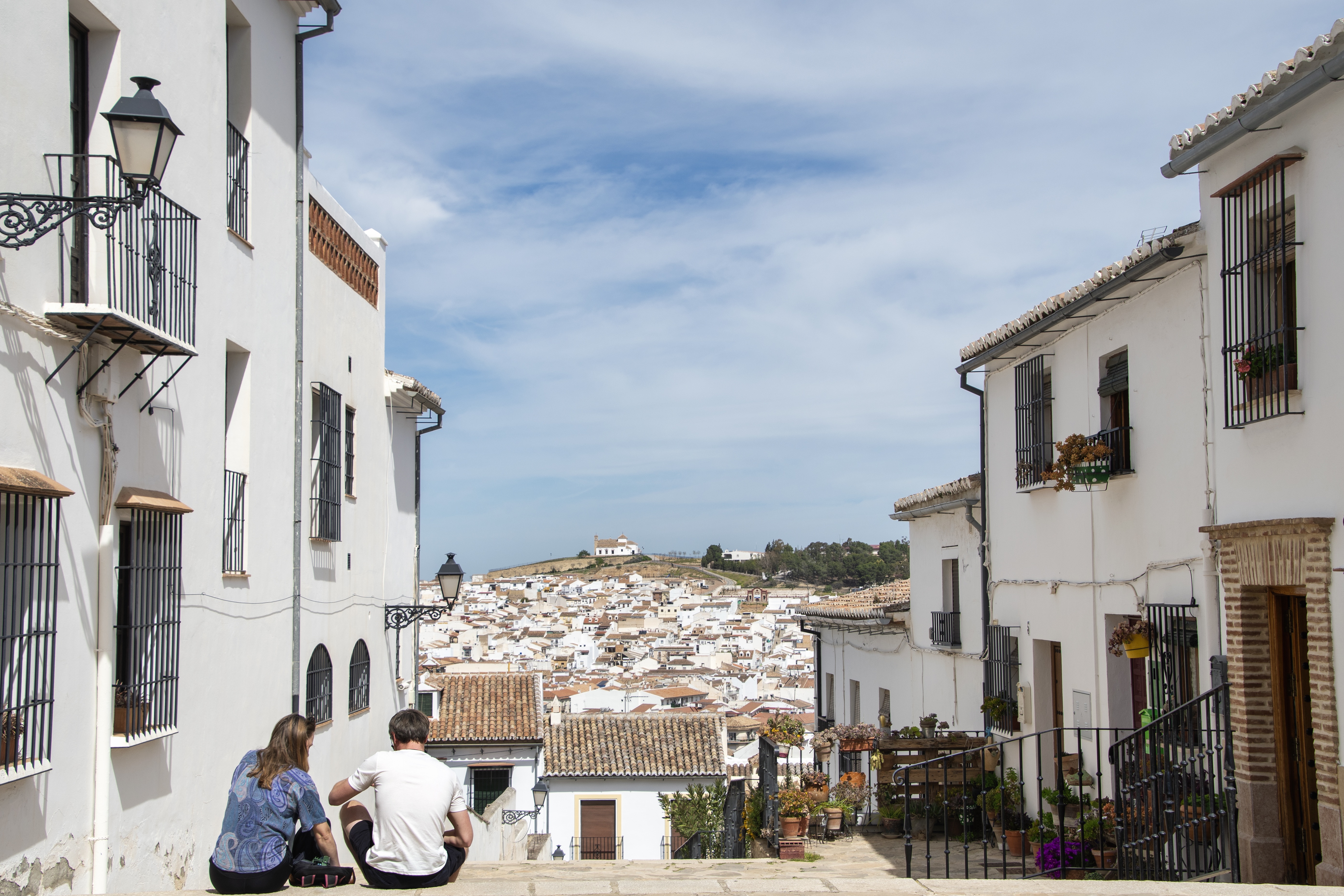 Two people sitting on steps in an Andalusian white village